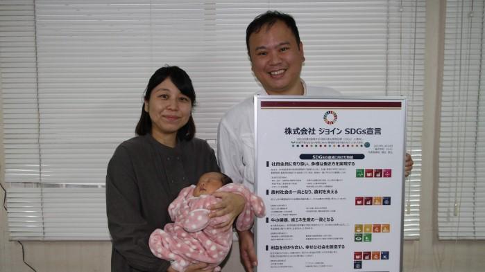 SDGs宣言を持つ細谷社長（右）と、先月生まれたばかりのみゆちゃんを抱く妻のゆかさん